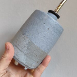 oliera in gres blu chiaro con due tonalità sovrapposte, con beccuccio in acciaio inox. E' tenuta in mano.
