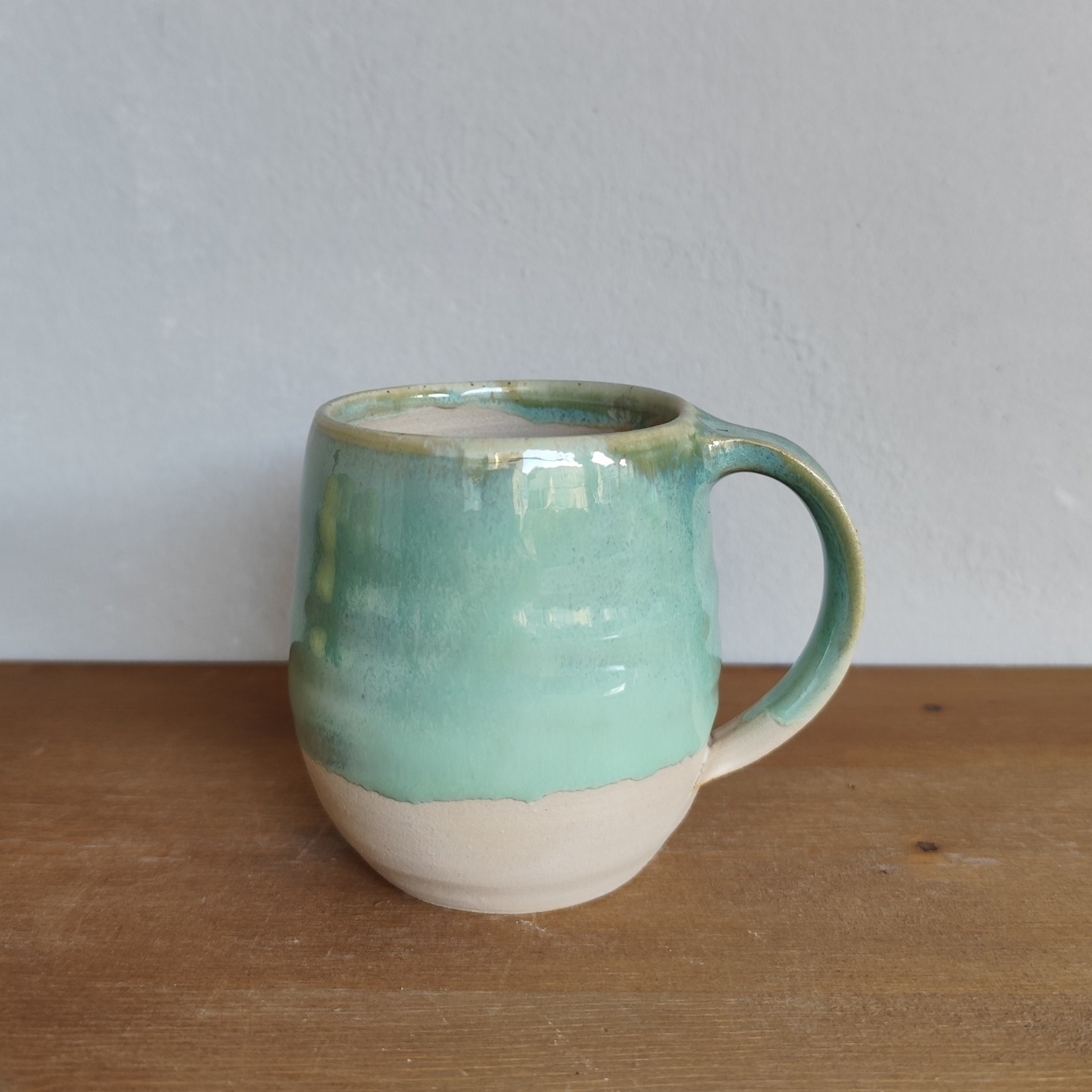 Tazza in ceramica fatta a mano al tornio, smalto verde acqua colato su base in gres a vista