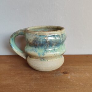 Tazza mug in gres fatta al tornio con rilievi e smalti lucidi verdi sovrapposti a base satinata sabbia